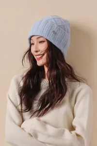 Detail of light blue cable knit wool beanie with classic ribbed edge and small metal logo