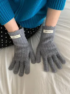 Detail of grey ribbed wool gloves with white ERET-WOOL woven label on the back