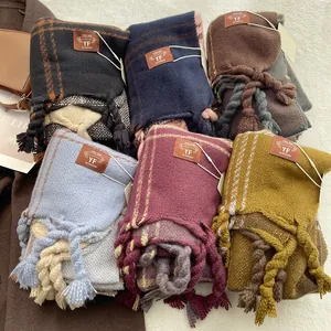 Detail of thick plaid scarves with fringes and leather label on soft white plush background
