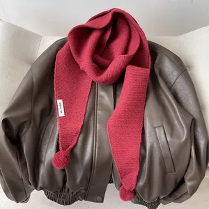 Detailed knit texture of solid red winter scarf with playful pom-pom ball decorations
