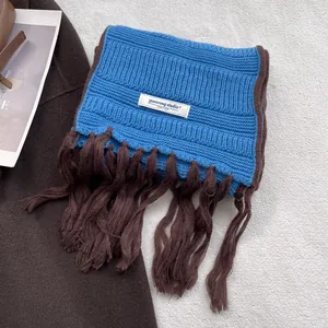 Detail of blue rib-knit scarf with thick brown twisted tassels and a white textile label