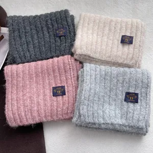 Chunky ribbed knit scarves in grey, beige, and pink displayed in an organized layout