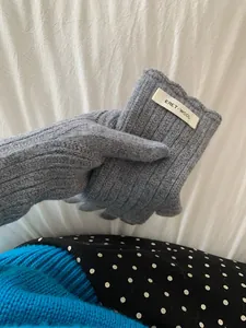 Detail of gray wool knit gloves featuring a classic ribbed cuff and branded fabric label