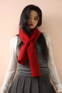 Detail of red knitted wool scarf styled with a grey vest and white shirt
