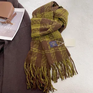 Detail of checkered knit scarf with long tassels, featuring brown and moss green texture
