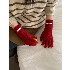 Merino wool red cable knit gloves for women featuring touchscreen tips and branded label