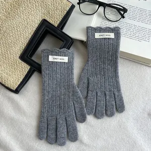 Close-up of gray wool knit gloves featuring ribbed texture and wave edge cuffs