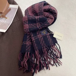 Detail of plaid tassel scarf with brand label and tag on soft textured background