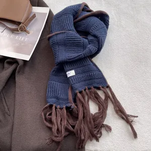Detail of blue ribbed knit scarf with brown fringe and studio tag on coat
