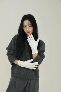 Close-up of white wool knit gloves with wavy cuffs and a branded Knit Wool label
