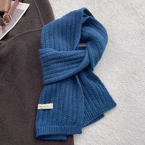 Dettaglio dell'etichetta 100% lana e della trama a maglia blu navy della sciarpa