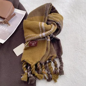 Detail of checkered knit scarf featuring thick braided tassels and yellow brown plaid