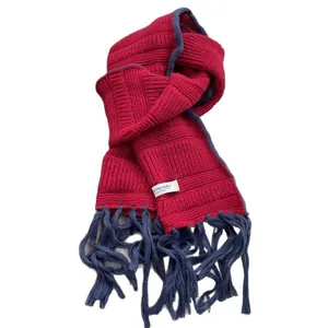 Deep red knit scarf with navy blue fringe trim and minimalist brand tag on plain background
