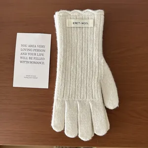 Close-up of cream wool knit gloves with vertical stripes and elegant wavy cuff details