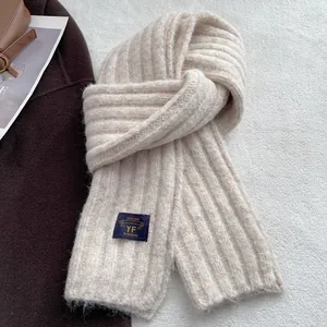 Detail shot of chunky knit scarf texture in beige with vintage brand label on top