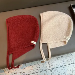Détail de cagoules en tricot 100% laine avec cache-oreilles en bordeaux et crème