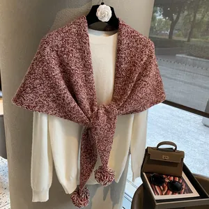 Thick burgundy and white knit wool triangle shawl with decorative pom-poms for winter