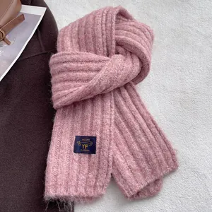 Detailed view of pink ribbed knit scarf texture featuring a navy brand logo woven label