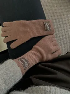 Close-up of dusty pink knit gloves featuring furry texture and stylish brown leather label