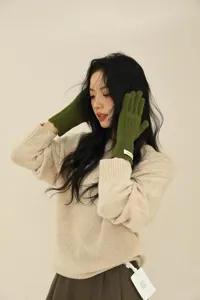 Close-up of olive green wool knitted gloves showing ribbed cuffs and warm texture