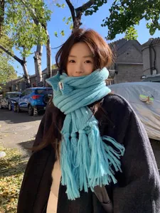 Close-up of sky blue thick knit scarf with long tassels and minimalist brand label