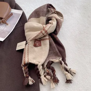 Macro detail of thick knit plaid scarf with braided tassels and premium leather brand tag