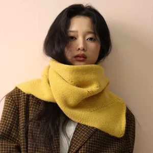 Bright yellow chunky knit scarf with button detail worn with a stylish wool coat