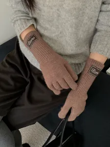 Detail of dark brown ribbed knit gloves with vintage logo patch and wrist cuff
