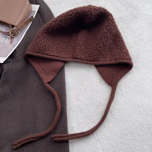 Détail d'une cagoule en laine marron foncé avec de longs lacets et texture épaisse
