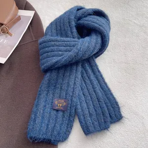 Detailed close-up of blue chunky knit scarf with texture and decorative fabric label