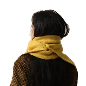 Knitted mustard yellow scarf for women featuring a stylish cross-loop wrap and thick texture