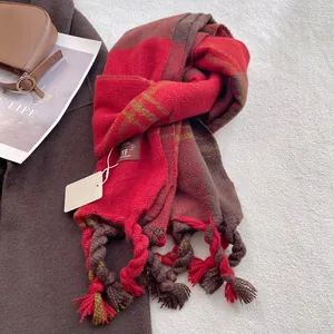Detailed close-up of thick plaid cashmere scarf with woven tassels and brand tag