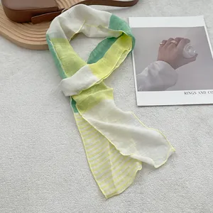 Lightweight striped linen scarf in yellow and green colors shown on a textured background