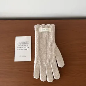 Detail of beige wool knit glove featuring vertical ribs and an ERET WOOL fabric label