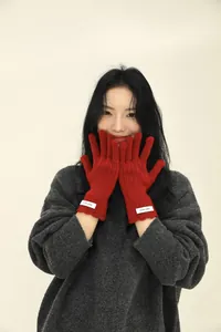 Close-up of red 100% wool knitted gloves with touch screen design and woven label