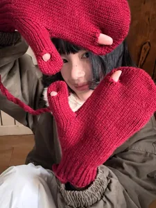 Détail de gants en maille rouge avec ouvertures aux doigts et cordon de cou pratique