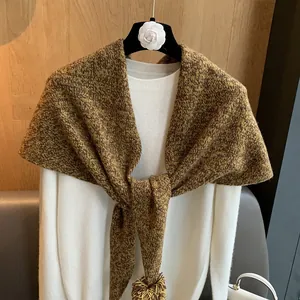Detalle del chal de lana con pompones y tejido texturizado en amarillo y marrón