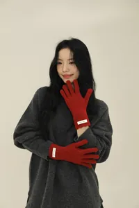 Close-up of red thick ribbed wool gloves with touch screen fingers and woven label