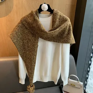 Detalle de un chal de lana marrón tejido con pompones en un interior acogedor