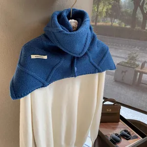 Close-up of a royal blue wool knit scarf showing a white logo tag and thick texture