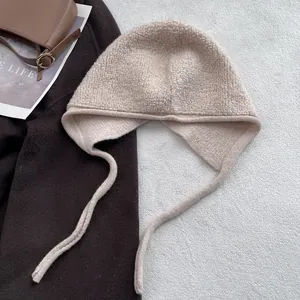Détail d'une cagoule en laine beige avec texture pelucheuse et protège-oreilles longs d'hiver