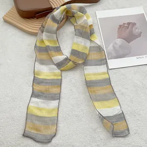 Macro view of a thin striped linen scarf with yellow and grey patterns on soft fabric