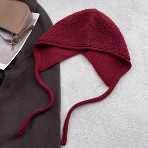 Détail de la cagoule en laine bordeaux avec lacets sur fond de tenue d'automne et d'hiver