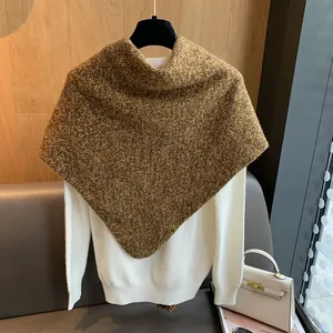 Detalle de chal de lana gruesa en marrón mezcla sobre un suéter de punto blanco