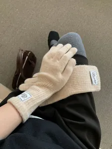 Detail of cream knitted gloves with vintage label on wrist for winter warmth