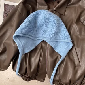 Détail à plat d'un bonnet en laine bleu clair avec protège-oreilles sur cuir