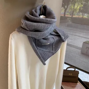 Detailed macro view of dark grey chunky knit scarf with button and braided cable texture