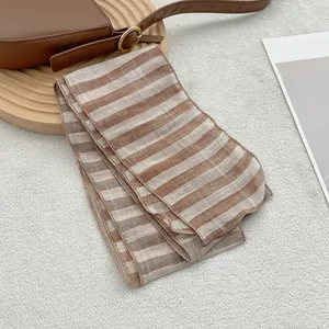 Detail of pure linen striped scarf texture and high-quality stitched edges on beige background