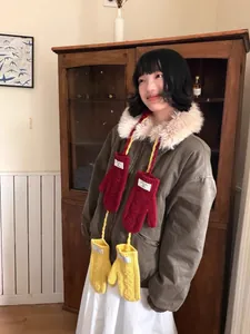 Détail de moufles en tricot tulipe avec cordon en rouge et jaune et étiquette tissée