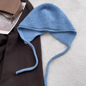 Détail de la cagoule en laine bleu clair avec protège-oreilles et cordons sur manteau marron